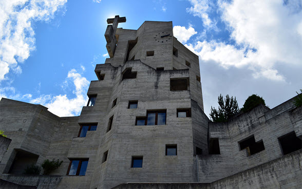 Das Bild zeigt den Glockenturm der Katholischen Kirche in Hérémence mit seiner Fassade in sorgfältig geschaltem Sichtbeton. 