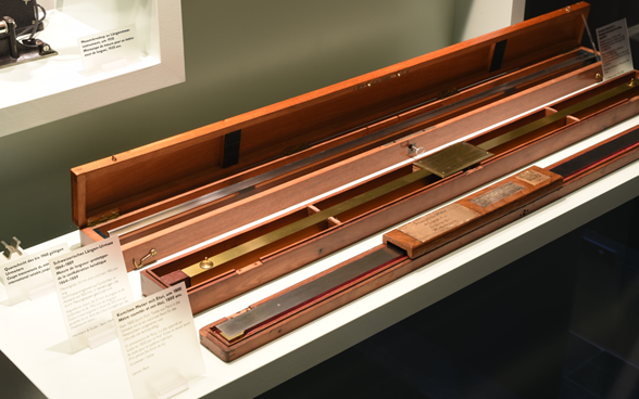 Zu sehen sind Holzbehälter, in denen drei Meter-Masse aus Metall aufbewahrt werden: die Kopie Nummer 2 des bis 1960 gültigen Urmeters in Paris, das schweizerische Längenurmass aus dem 19. Jahrhundert und der Komitee-Meter um 1800.