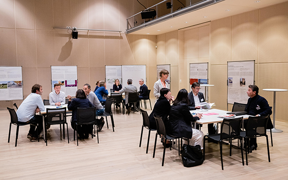 Une personne prend des notes sur un tableau, d'autres participants à l'atelier discutent en arrière-plan